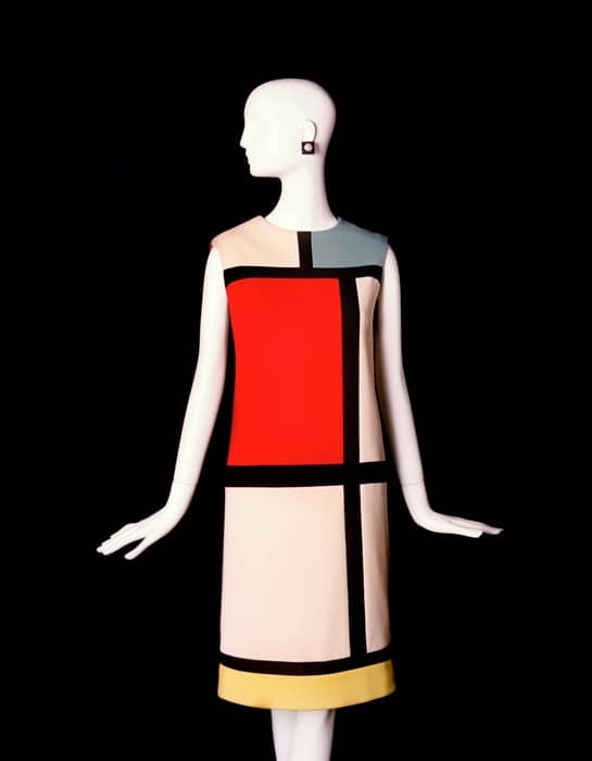 Yves Saint Laurent shift dress inspired by Piet Mondrian De Stijl style, blocks of colour red, cream, yellow, black. Dress on a white mannequin with a black background.