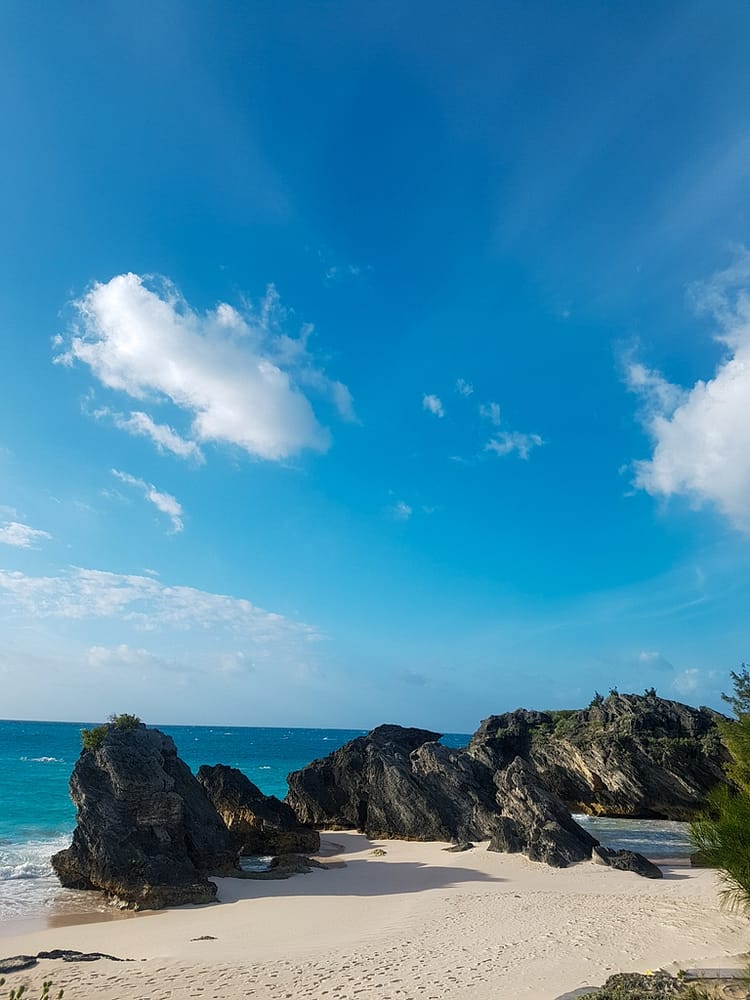 Blue sky, sea and sand with rocks along the seafront at Middle Beach, Bermuda.