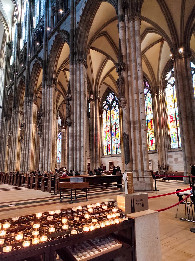 Inside pillars and architecture of Kölner Dom (Cologne Cathedral) with candles lighting