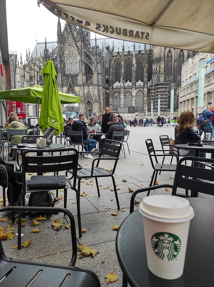 View of Kölner Dom (Cologne Cathedral) from coffee shop on square while sitting with a Starbucks mug on the table