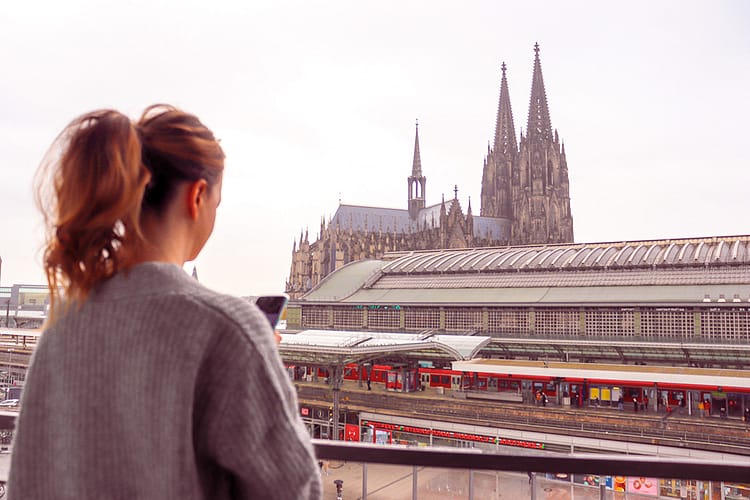 Anita Kenna standing with back to camera looking over view of Cologne train station and Kölner Dom (Cologne Cathedral)