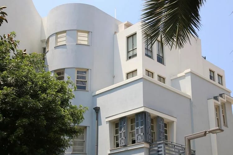Bauhaus style white cement building surrounded by trees in Tel Aviv, Bauhaus style building