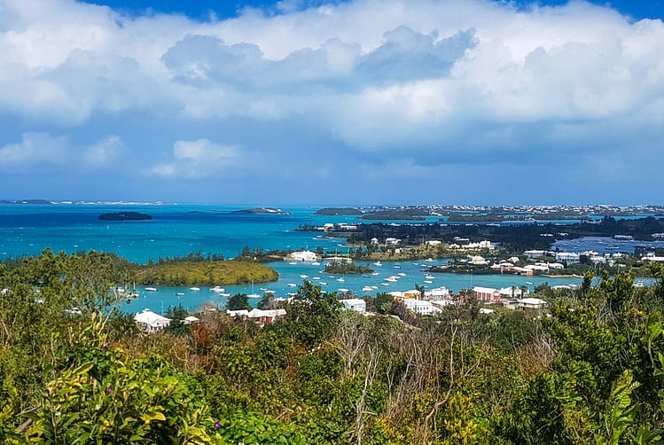 View of Bermuda island from Queens View at Gibb's Hill Lighthouse. Greenery, building tops, sea and boats.
