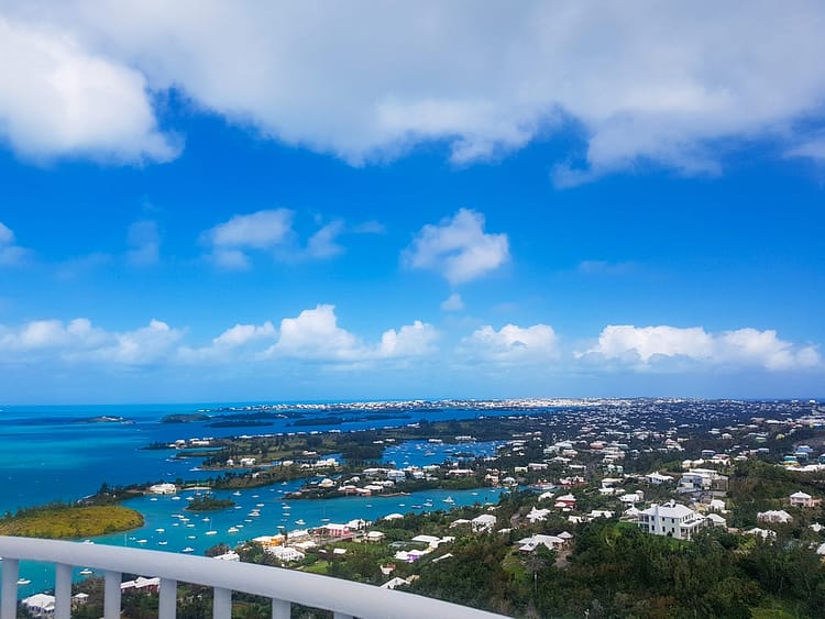 View overlooking Bermuda island from the top of Gibb's Hill Lighthouse. Greenery, rooftops and blue sea.
