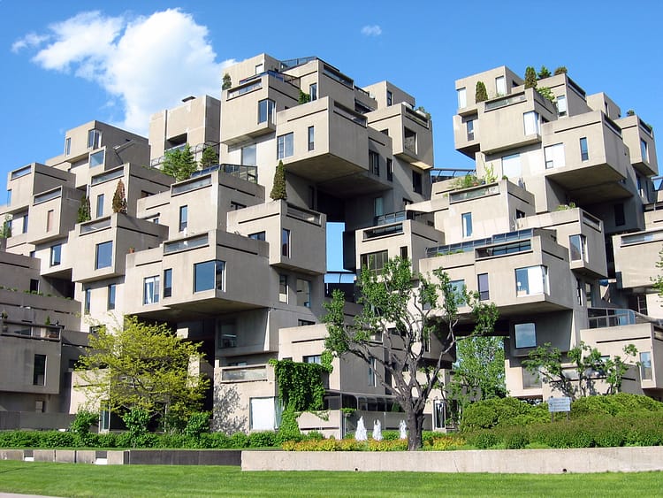 Stacked Apartment block by Moshe Safdie, block of stacked apartments surrounded by green grass and trees