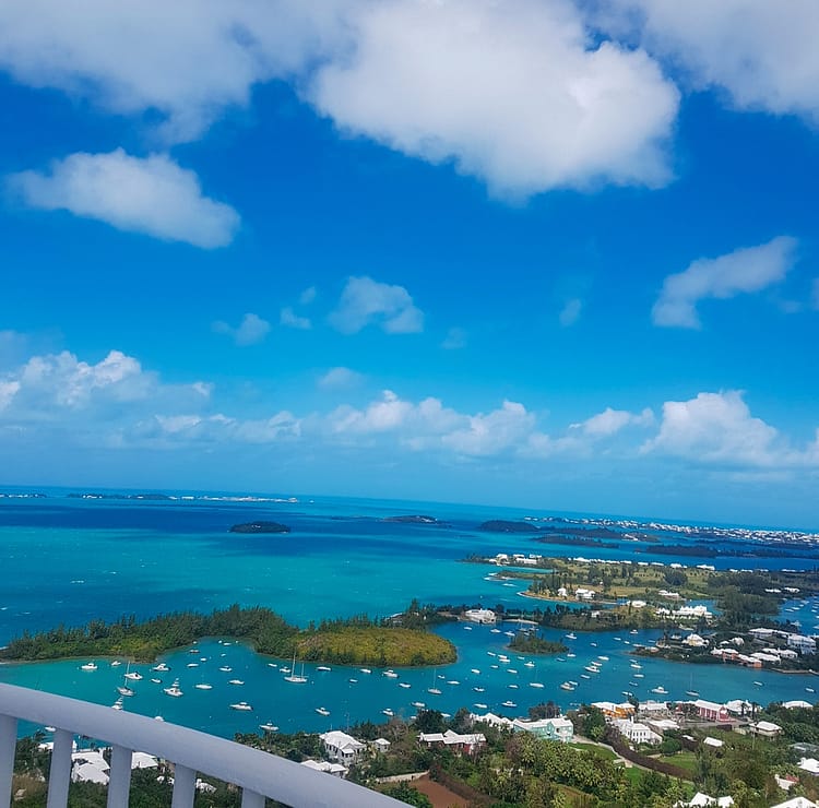 View overlooking Bermuda island from the top of Gibb's Hill Lighthouse. Greenery, rooftops, blue sea and white boats..