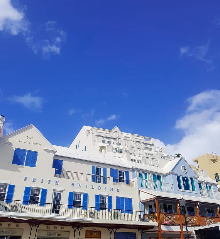 Frith white building with blue window shutter frames on Front Street, Bermuda. Blue sky over the building accounts for half the image.