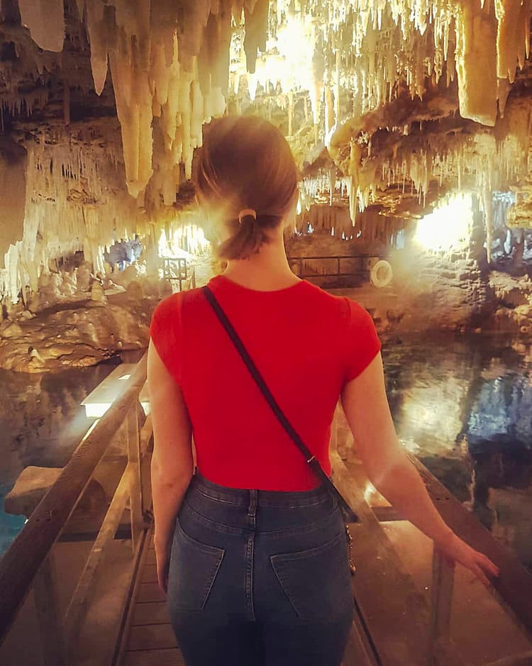 Back of girl in red top walking through Crystal Cave, Bermuda.